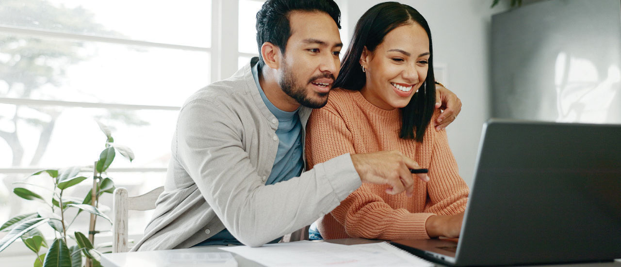 A couple sitting at a laptop computer reviewing their loan offer