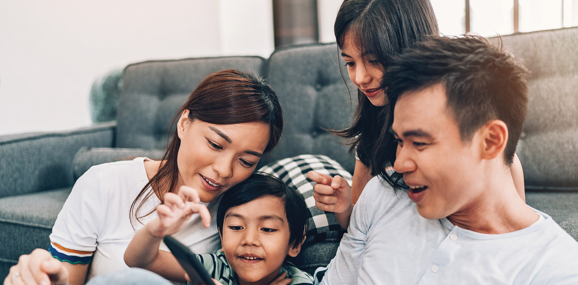 A young family sitting on floor looking at smart device